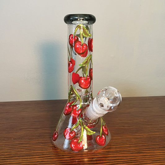 This is an 8 in beaker bong that is hand painted with cherries with green stems scattered all around the bong. The top rim of the bong is a black stained glass.