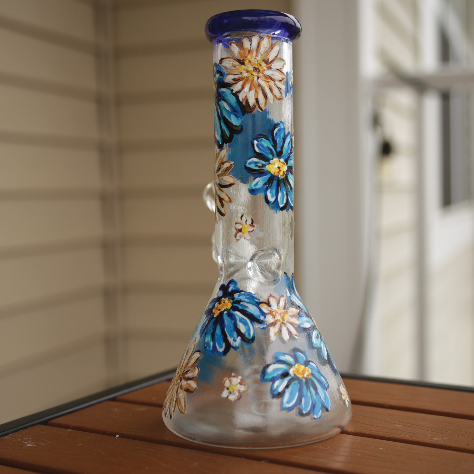 Back view of a 9 inch clear beaker bong with painted blue and white flowers with a blue rim top and ice catcher.