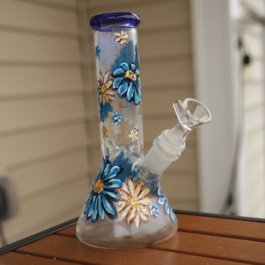 Front view of a 9 inch clear beaker bong with painted blue and white flowers with a blue rim top and ice catcher.